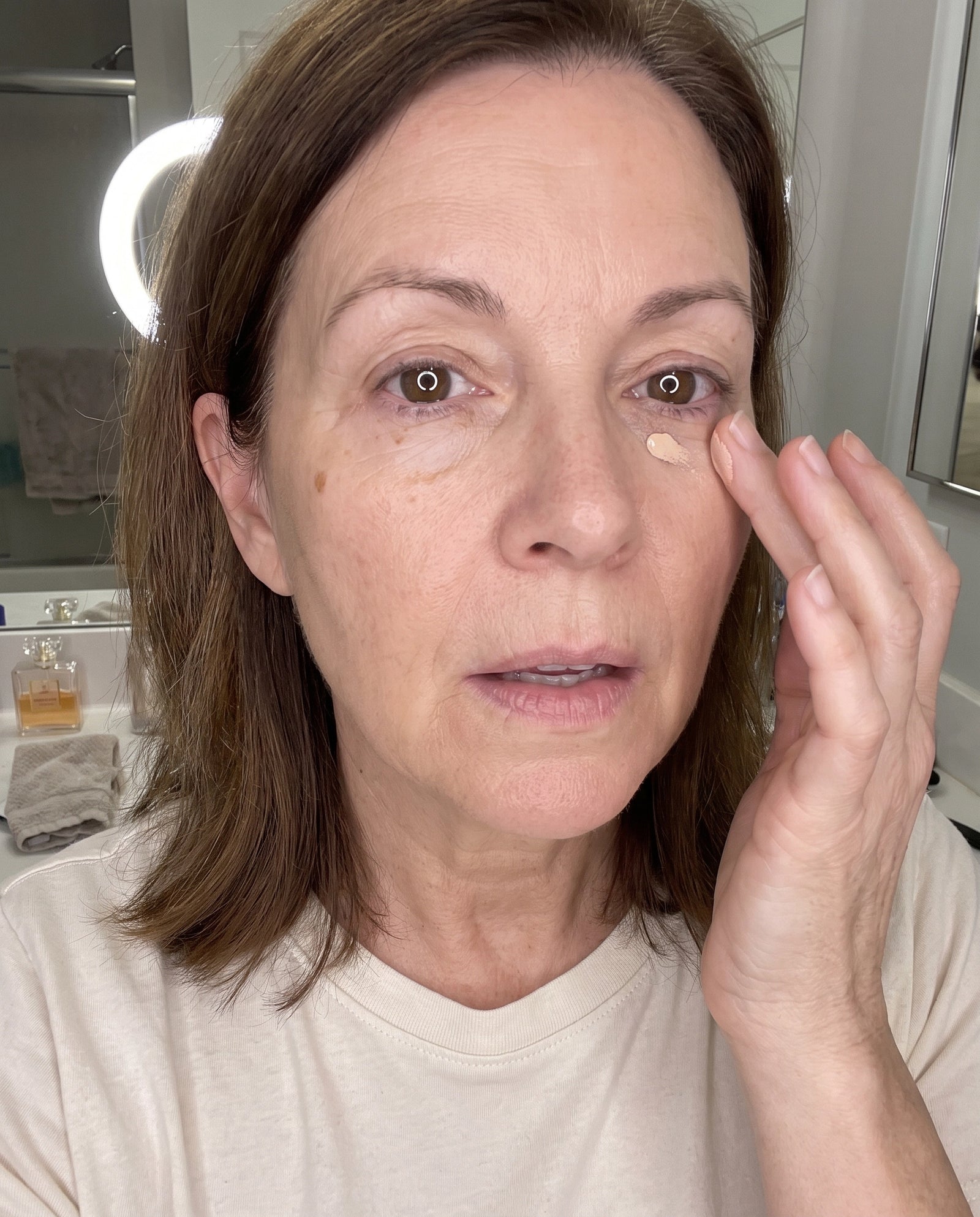 Woman 65+ patting concealer under her eye with her ring finger